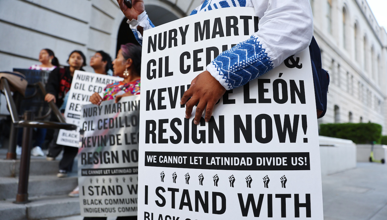 Pictured: Protesters hold signs that call for the resignation of Nury Martínez, Gil Cedillo, and Kevin De León. Photo by Mario Tama/Getty Images