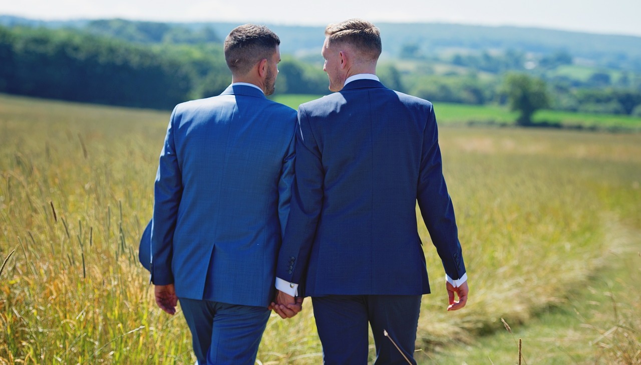 Recently married gay couple walking in a countryside road. 