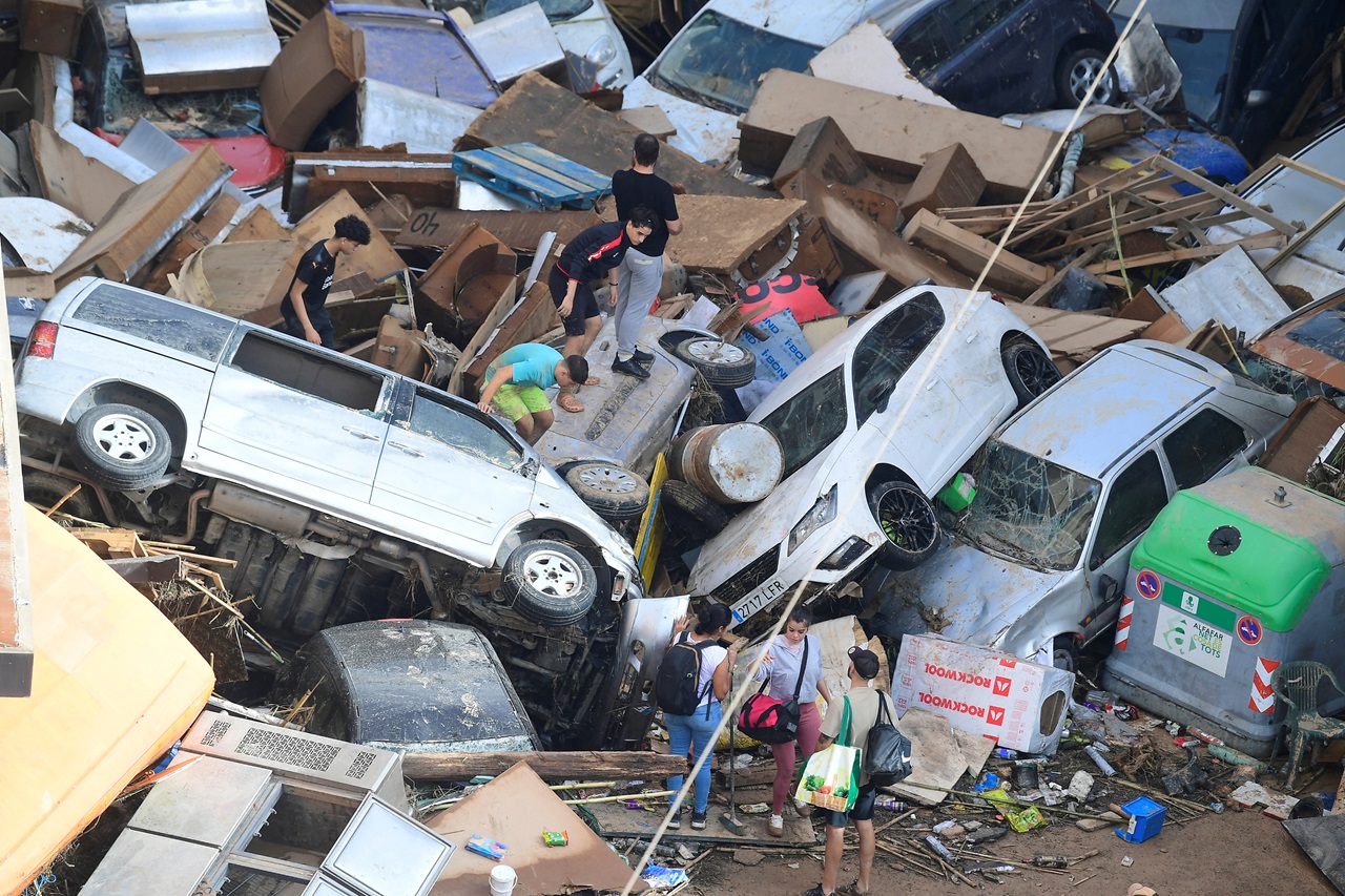 Personas suben a coches apilados tras las inundaciones en Sedavi, al sur de Valencia, este de España. Las inundaciones provocadas por las lluvias han dejado al menos 90 muertos, según informaron los servicios de rescate. (Foto de Jose Jordan / AFP)