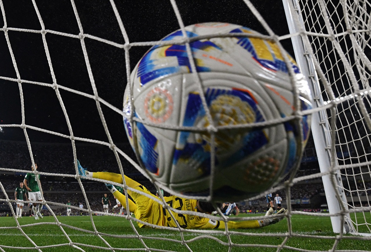 A soccer ball in the goal net. Photo by AFP