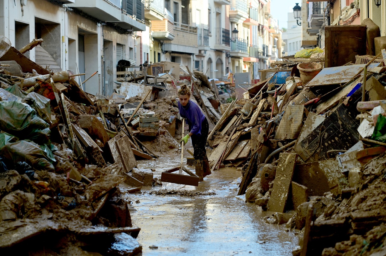 A woman sweeps water from her street in Valencia after Dana, the weather phenomenon that affected this Spanish town (Photo by JOSE JORDAN / AFP).