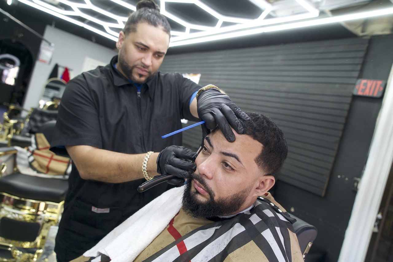 Kenny Ramirez, a Dominican-American barber who voted for Donald Trump in the 2024 US presidential election, trims and cuts the hair of Francis Rodriguez, a warehouse worker who voted for US Vice President Kamala Harris, in Reading, Pennsylvania. (Photo by Bastien INZAURRALDE / AFP)