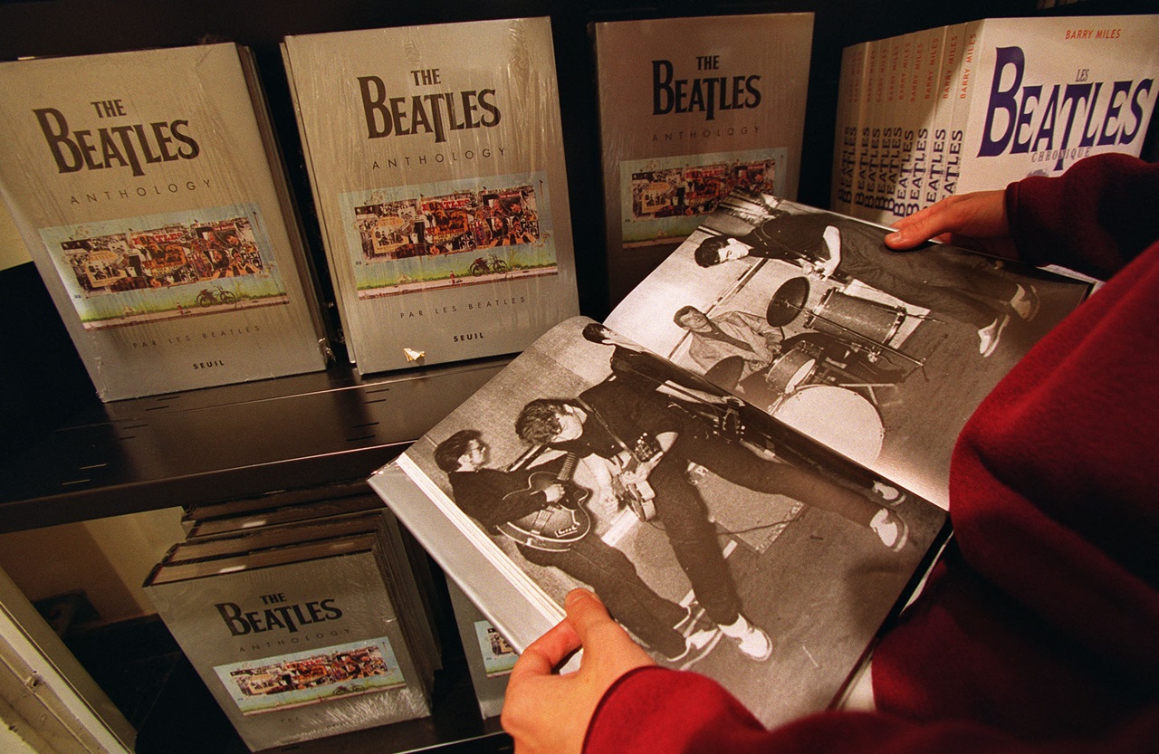 A fan reads the book "The Beatles Anthology" in 2000 (File photo by FRANCOIS GUILLOT / AFP).