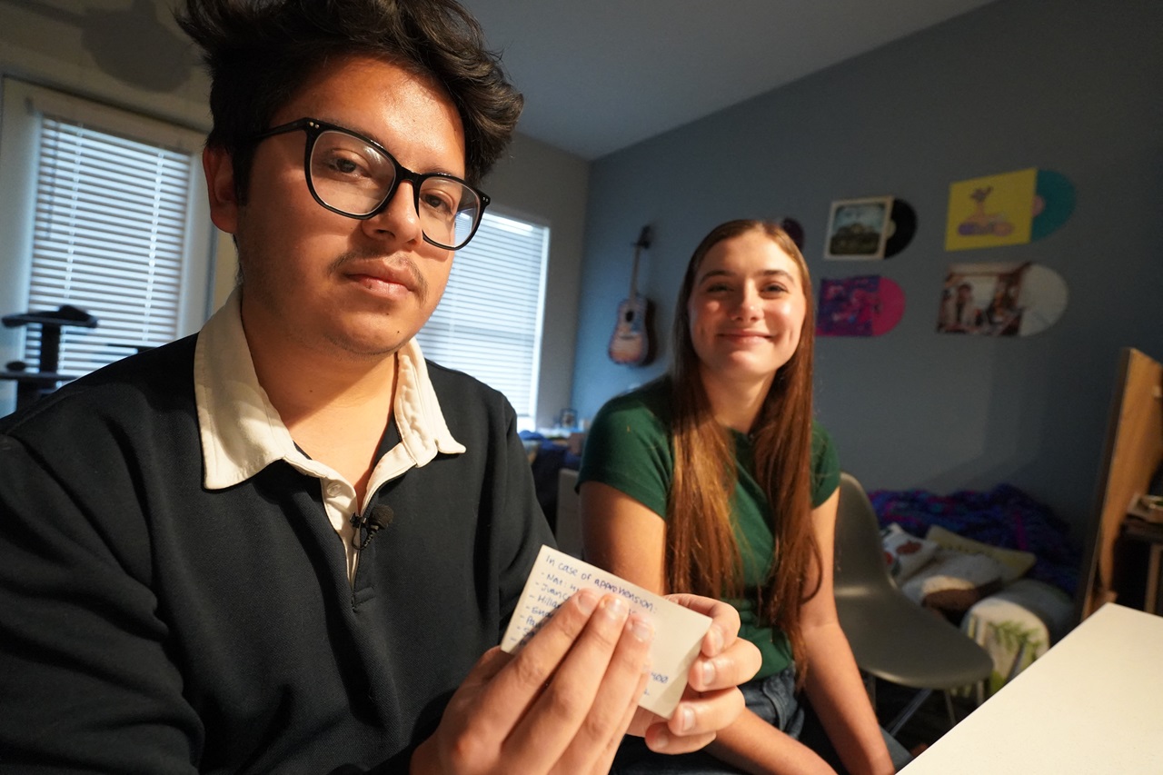 Oscar Silva (24) with his wife Natalie Taylor (23) shows a card he keeps in his wallet with the contacts he must give to the authorities to notify his wife, family and lawyer, in case he is detained for possible deportation, in Denton, Texas, on December 8, 2024. (Photo by Francois PICARD / AFP)