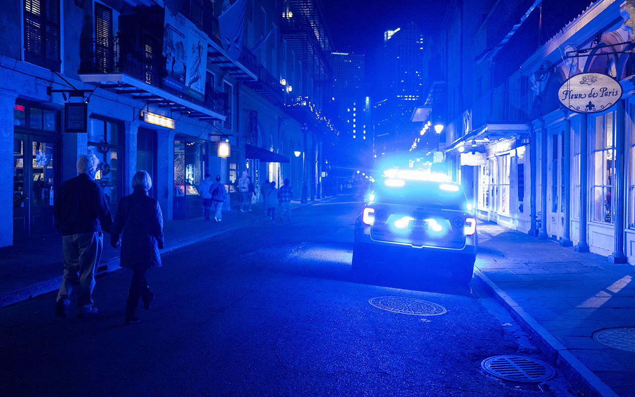 A couple pass a police car in the French Quarter after at least 15 people were killed on Bourbon Street during an attack early in the morning on January 1, 2025 in New Orleans, Louisiana. (Photo by ANDREW CABALLERO-REYNOLDS / AFP)