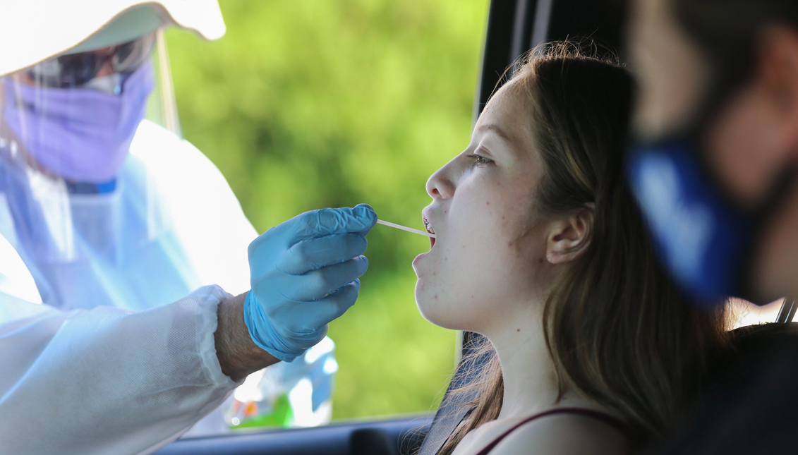 LOS ÁNGELES, CALIFORNIA - 11 DE AGOSTO: Un trabajador de la salud le hace a una niña un examen de garganta en un centro de pruebas de coronavirus (COVID-19) en la Escuela de Sufismo Islámico M.T.O. Shahmaghsoudi el 11 de agosto de 2020 en Los Ángeles, California. California reportó 12.500 nuevos casos después de que los casos atrasados de una falla de datos comenzaron a aparecer en el sistema del estado. (Foto de Mario Tama/Getty Images)