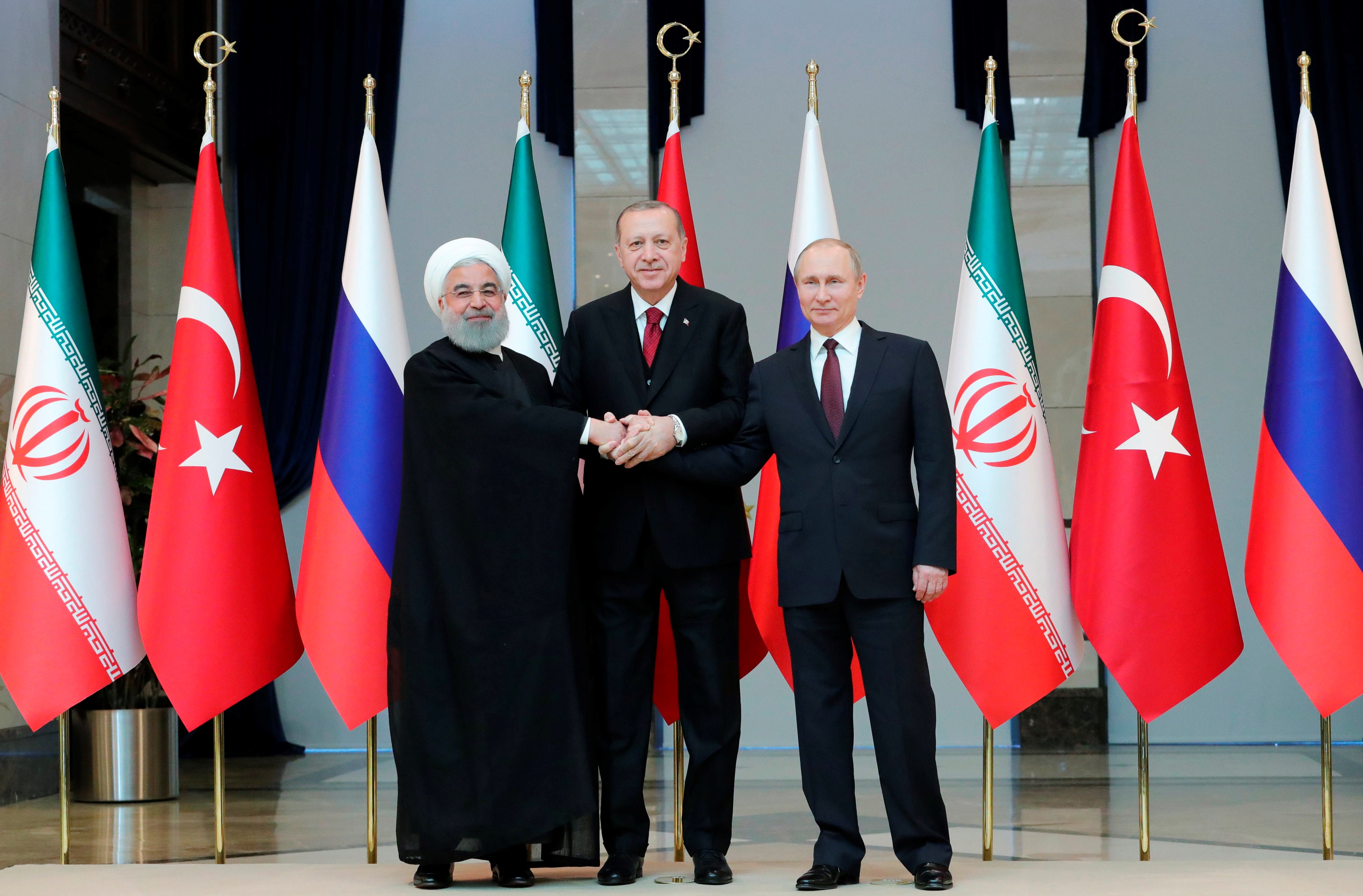 Turkish President Recep Tayyip Erdogan (C), Russian President Vladimir Putin (R) and Iranian President Hassan Rouhani (L) join hands as they pose for a family photo during their meeting at the Presidential Palace in Ankara, Turkey, Apr. 4,l 2018. EPA-EFE/MIKHAIL KLIMENTYEV/SPUTNIK/KREMLIN / POOL
