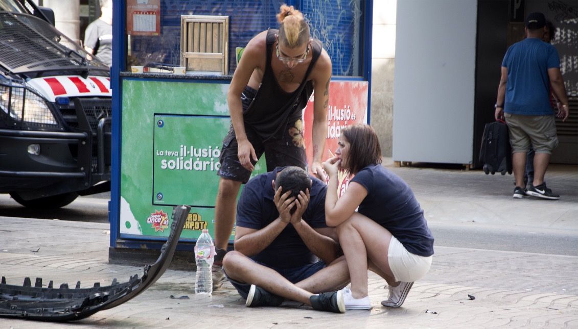 Varios jóvenes permanecen junto a los restos de un vehículo, en el lugar del atropello masivo realizado por una furgoneta que ha arrollado esta tarde a varias personas que paseaban por las Ramblas de Barcelona. EFE