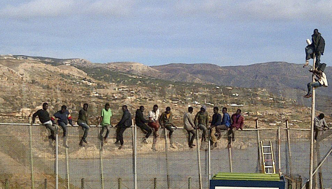 Unos 25 inmigrantes de origen subsahariano permanecen encaramados en la parte alta de la valla de Melilla y forman parte de un grupo que ha intentado acceder a la ciudad autónoma sobre las 09.00 horas. Los inmigrantes están en la zona de Aguadú, la parte más al norte del perímetro de Melilla. EFE
 
 
