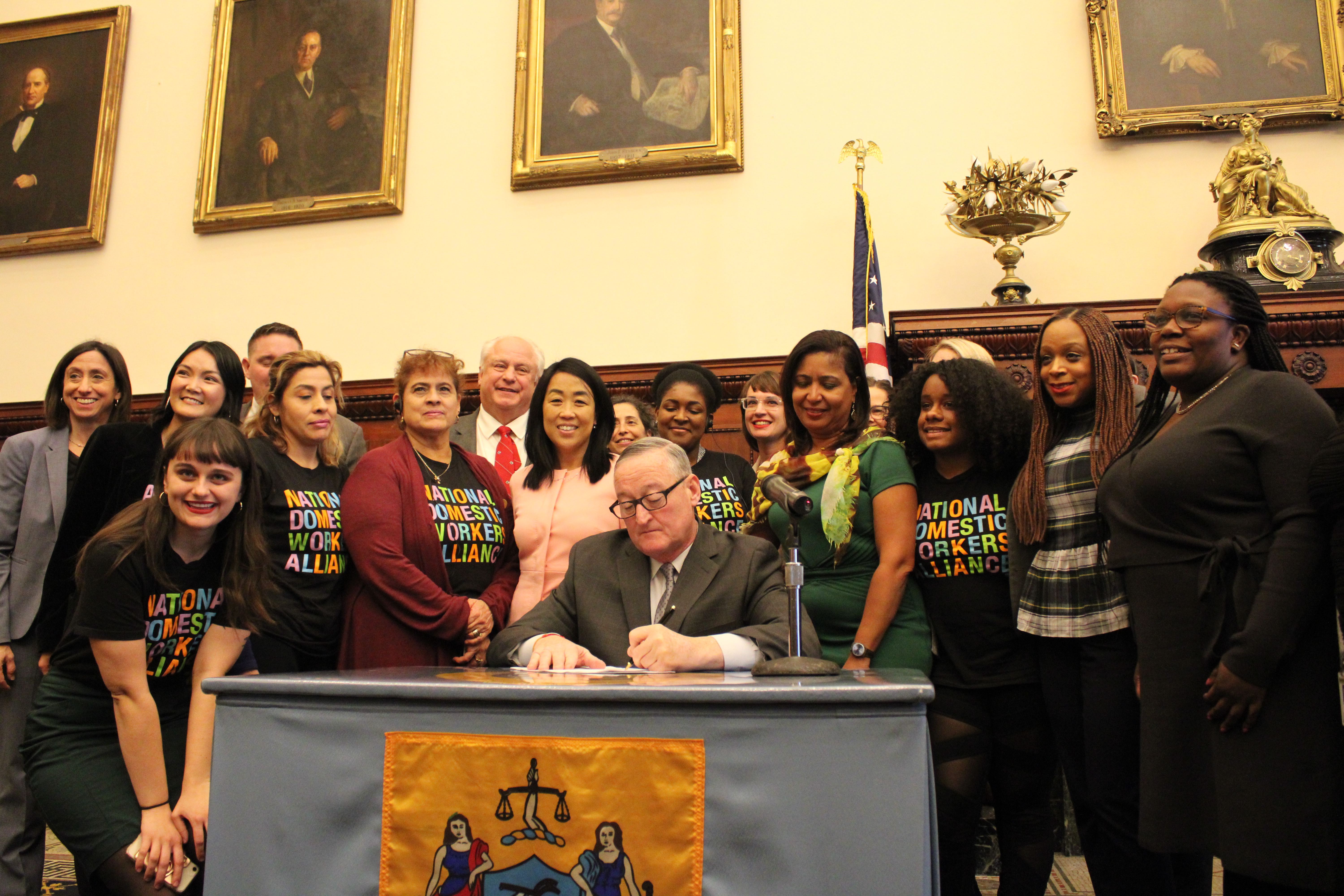 Mayor Jim Kenney (center) signs the Philadelphia Domestic Workers Bill of Rights as domestic workers, organizers, leaders, and elected officials look on. Photo: Emily Neil / AL DÍA News