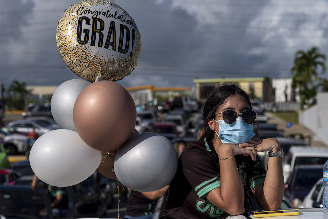 A graduating student from the Ramon Power Y Giralt High School wears a facemask during a symbolic graduation from their cars to maintain social distance at a parking lot in Las Piedras, Puerto Rico, on May 13, 2020. Photo: Ricardo Arduengo/AFP via Getty Images.