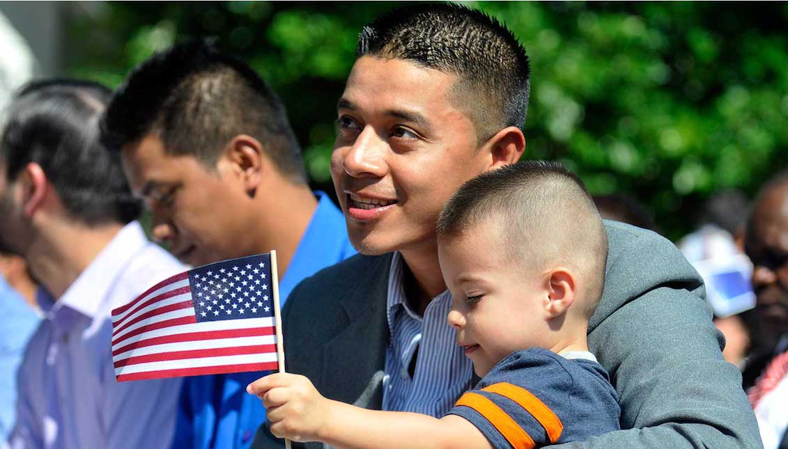 A father holds his child during a naturalization ceremony in Greeley, Colorado, on July 3, 2014. (AP Photo/The Greeley Tribune / Joshua Polson)