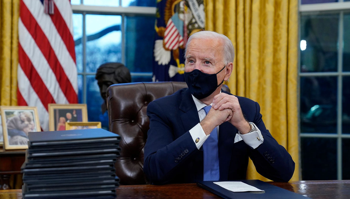 Biden and his stack of executive actions. Photo: Evan Vucci/AP News
