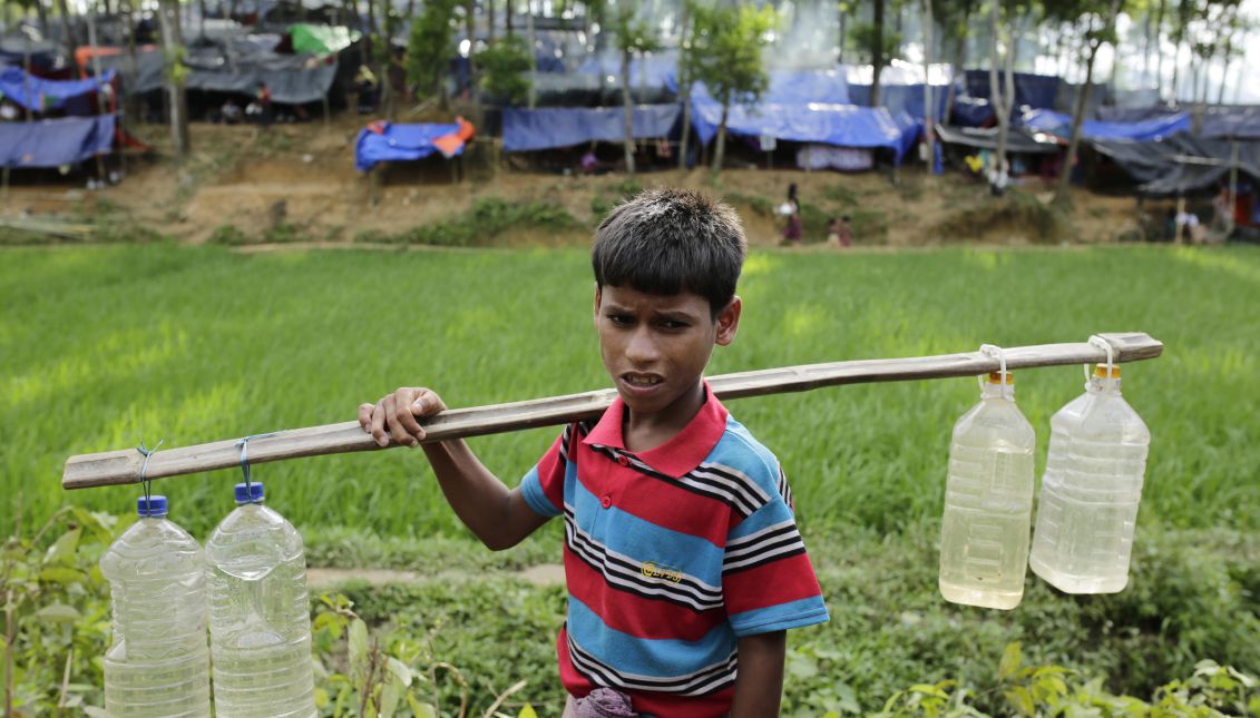 A Rohingya boy stands on a street carrying bottles of water in front a newly built camp in Ukhiya, Cox's Bazar, Bangladesh, Sept. 11, 2017. EPA/ABIR ABDULLAH
