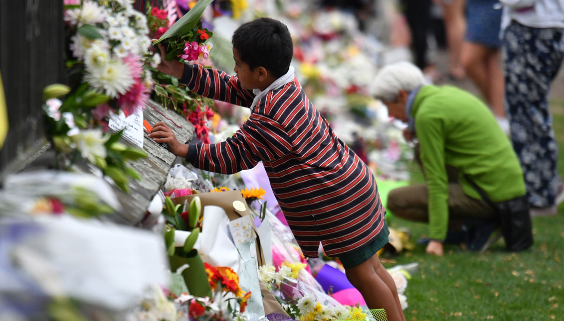 A child places flowers at a makeshift memorial for the victims of the mosque mass murders at the Botanical Gardens in Christchurch, New Zealand. EFE
