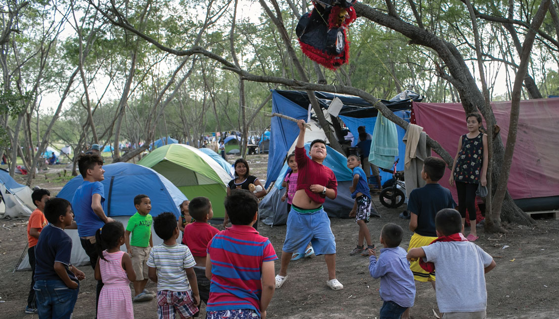 Niños inmigrantes rompen una piñata de cumpleaños en un campamento para solicitantes de asilo el 09 de diciembre de 2019 en la ciudad fronteriza de Matamoros, México. Más de 1,000 solicitantes de asilo centroamericanos y mexicanos se han estado quedando, muchos de ellos durante meses entre audiencias en la corte de inmigración, en un escuálido campamento en Matamoros, al otro lado de la frontera de Brownsville, Texas. (Foto de John Moore/Getty Images)
