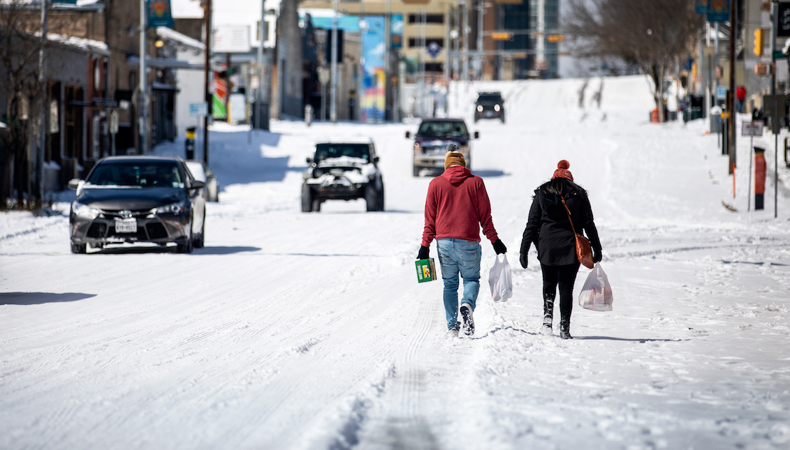 AUSTIN, TX - FEBRUARY 15: People carry groceries from a local gas station on February 15, 2021 in Austin, Texas. Winter storm Uri has brought historic cold weather to Texas, causing traffic delays and power outages, and storms have swept across 26 states with a mix of freezing temperatures and precipitation. (Photo by Montinique Monroe/Getty Images)