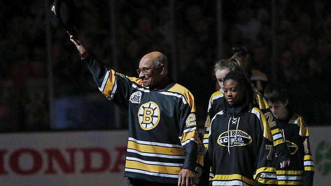 Willie O'Ree, the first Black player to play in the National Hockey League, greats fans with young hockey players behind him. Photo: Getty Images.