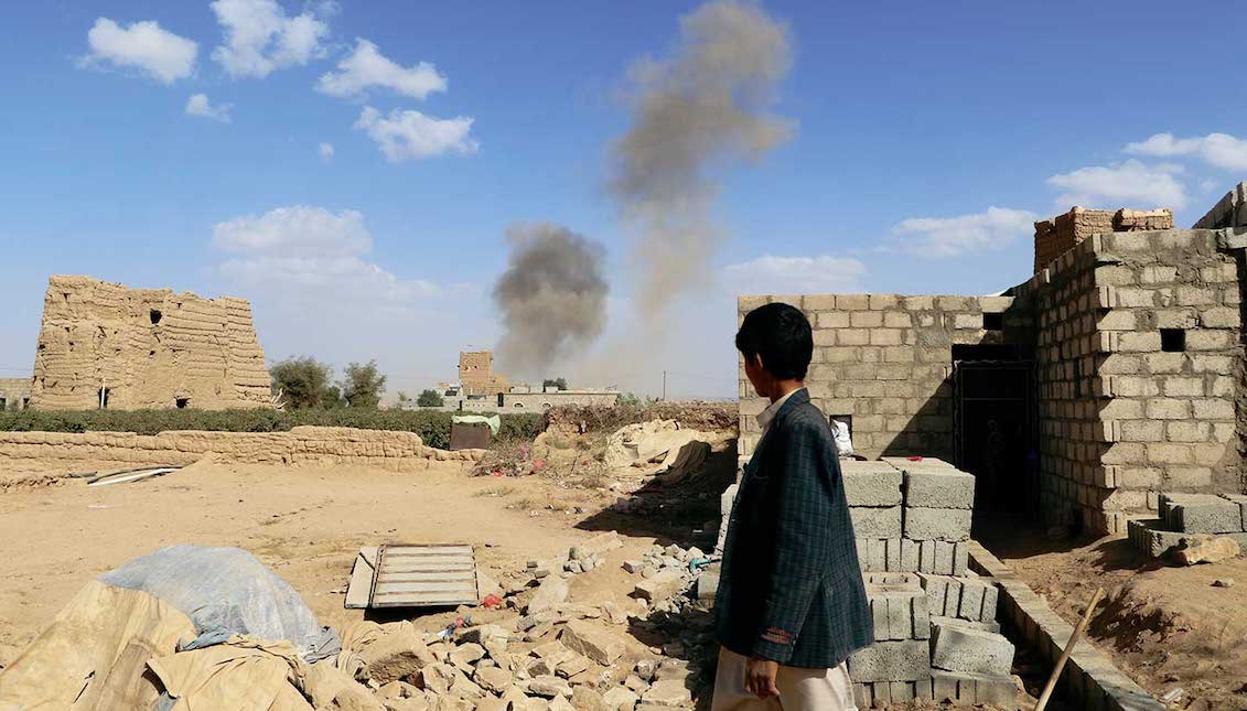 Un niño observa el polvo que se levanta desde el lugar de los ataques aéreos en Saada, Yemen, el 27 de febrero de 2018. (Reuters/Naif Rahma)