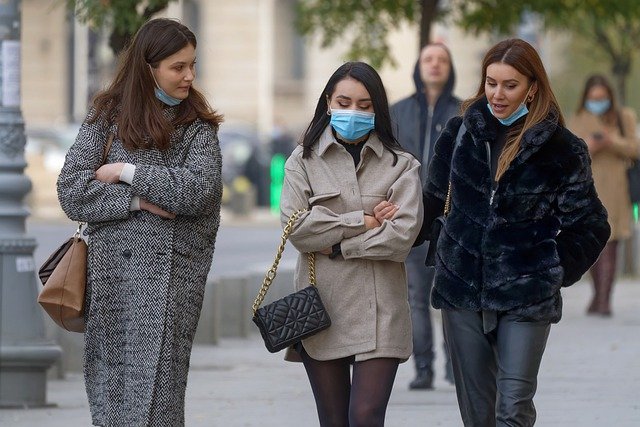 Women walk on the street wearing covid masks