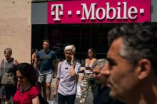 Pedestrians cross an intersection near a T-Mobile store on Sixth Avenue in Manhattan on July 26, 2019 in New York City. (Photo by Drew Angerer/Getty Images)